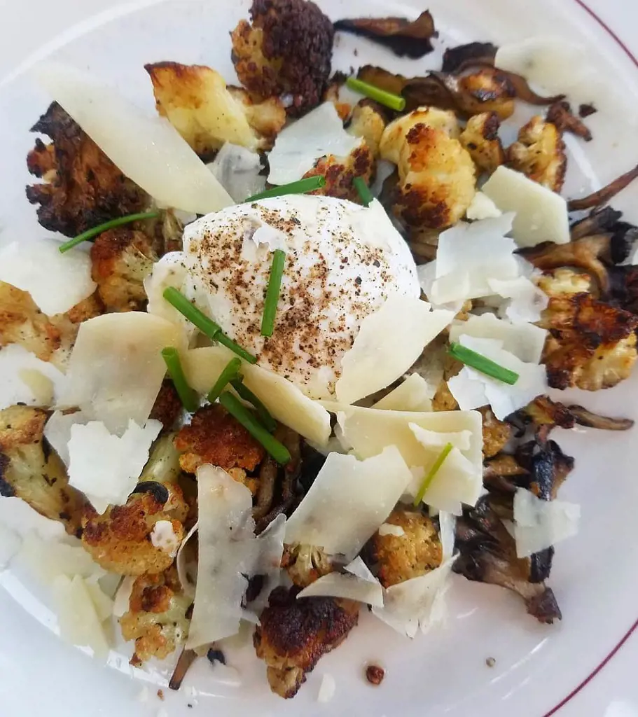 Roasted Local Cauliflower with shaved Piave and woods mushrooms on the plate.